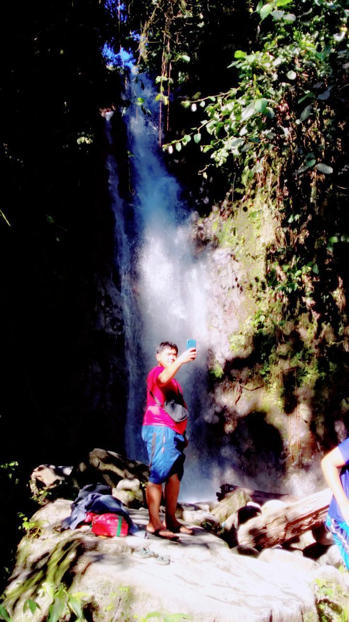 FULL LENGTH OF BOY STANDING BY WATERFALL