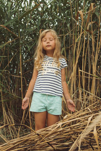 Girl looking away while standing against plants