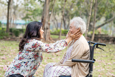 Smiling granddaughter embracing grandmother at park