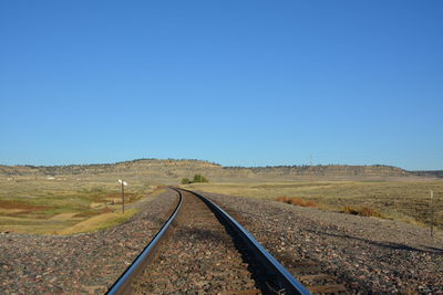 Surface level of railroad track against clear blue sky