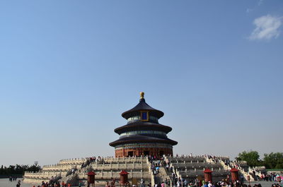 Crowd outside temple against clear blue sky