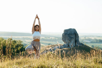 Woman meditating and practicing yoga outdoors at sunset and nature miracle giant stone