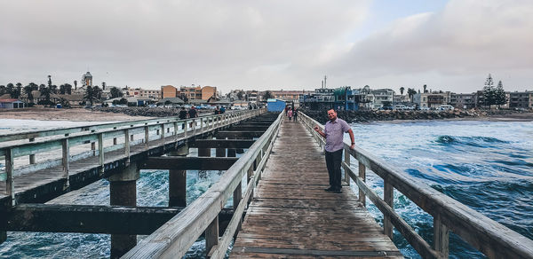 Man standing on bridge over canal against sky