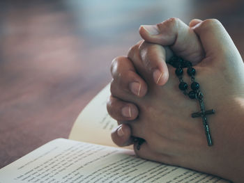 Cropped image of person with hands clasped on book