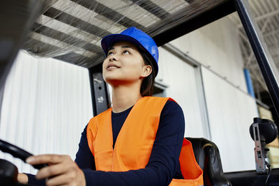 Female worker on forklift in factory looking up