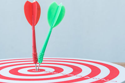 Close-up of arrow on dartboard against white background