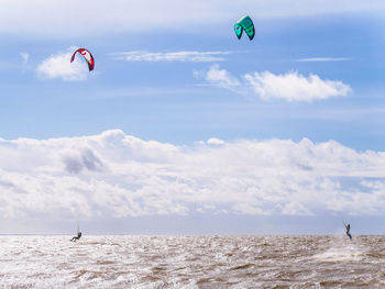 People paragliding over sea against sky