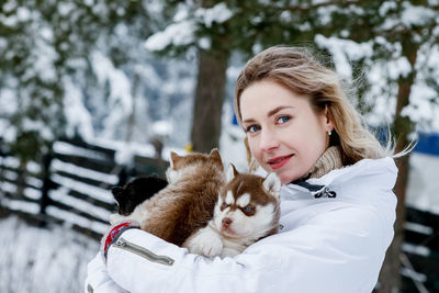 Portrait of young woman with puppies during winter