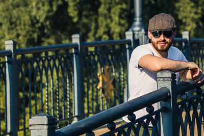 Portrait of young man standing by railing