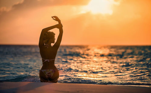 Man standing on beach against sky during sunset