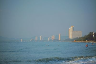 Sea by buildings against clear sky