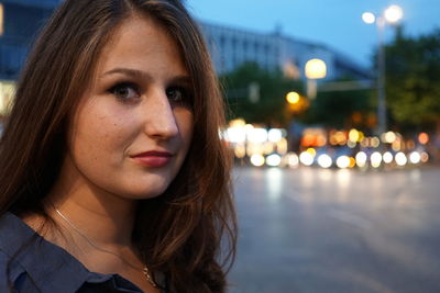 Portrait of young woman standing on street at dusk