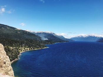 Scenic view of sea and mountains against blue sky