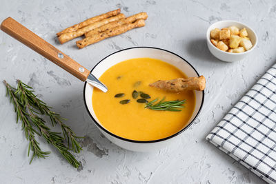 Pumpkin and carrot soup with cream, pumpkin seeds, croutons and grossini bread sticks 