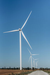 Wind turbines on field against clear blue sky