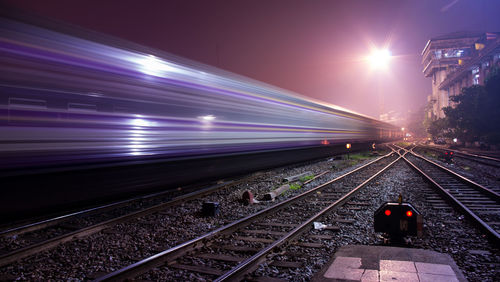 Train on railroad tracks against clear sky at night