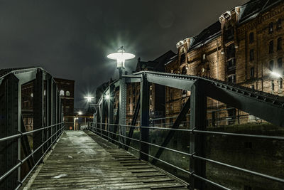 Illuminated walkway in city at night