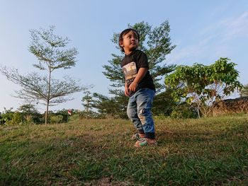 Full length of boy standing on field against sky