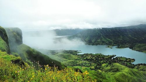 Scenic view of river and green mountains against sky