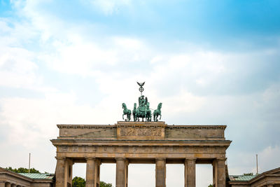 Low angle view of brandenburg gate against cloudy sky