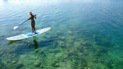 High angle view of woman in bikini paddleboarding in sea