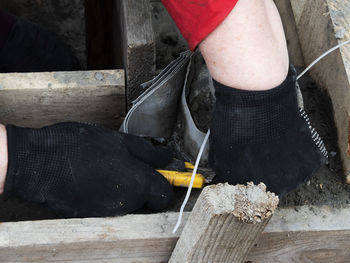 Gloved hands of a worker cutting a soft formwork from columns in a strip-column foundation