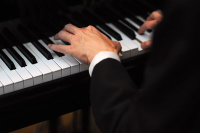 Cropped hands of man playing grand piano