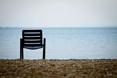 Close-up of deck chair on beach against clear sky