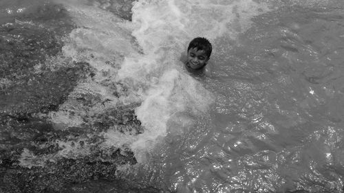 High angle view of smiling boy swimming in sea