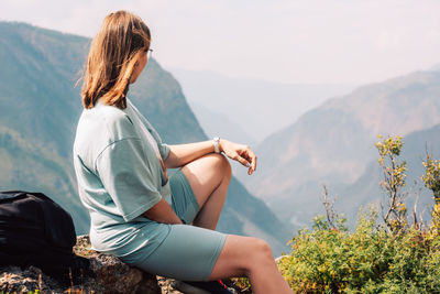 Side view of woman sitting on mountain