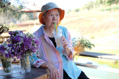 Senior woman drinking juice while looking away at cafe