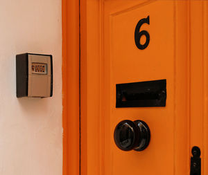 Smart key lock mounted on wall for renting apartment. safe key box.orange vintage door with number 6