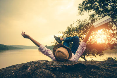 Man sitting on land against sky during sunset