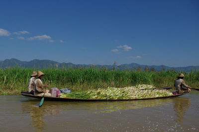 Side view of farmers carrying crops in boat 