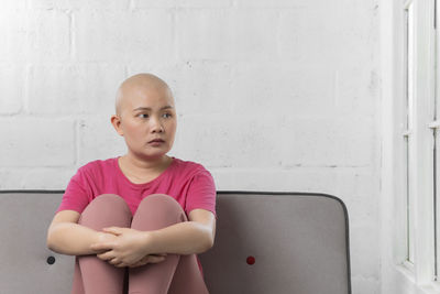 Portrait of boy sitting against wall at home