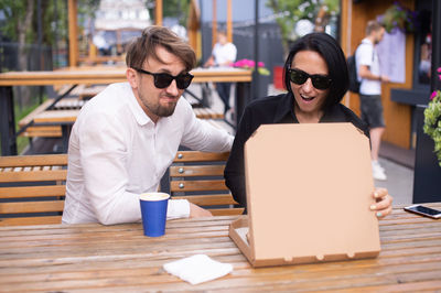 Husband and wife came to lunch at a pizzeria. opening a pizza box