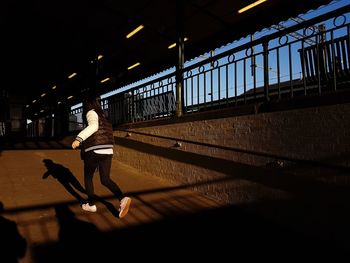 Full length of woman on illuminated bridge against sky in city