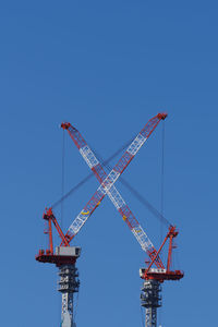 Low angle view of crane against clear blue sky