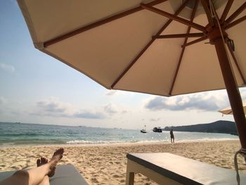 Low section of person on beach against sky