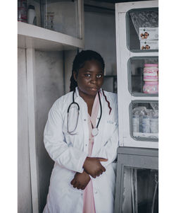 Portrait of female doctor standing against wall