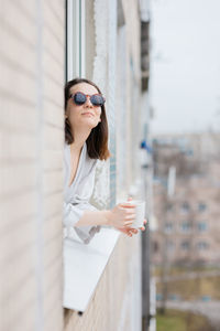 Portrait of woman looking out through window