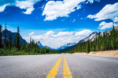 Road by trees against sky