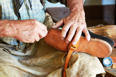 Close-up midsection of man sewing shoe