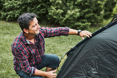 Man putting up a tent at camping during summer vacation. preparing campsite to rest and relax