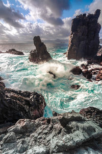 Scenic view of rocks in sea against sky