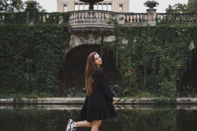 Woman standing by tree against water