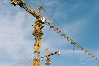 Low angle view of crane at construction site against sky