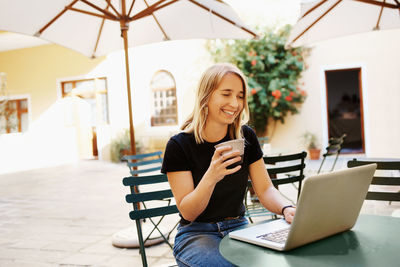 Smiling woman using laptop in cafe