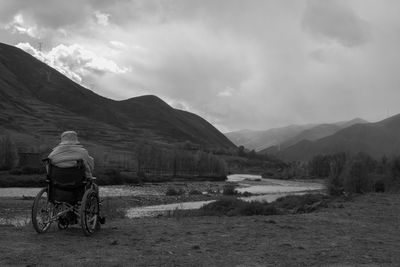 Rear view of man cycling on mountain against sky