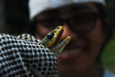 Close-up of young man holding snake